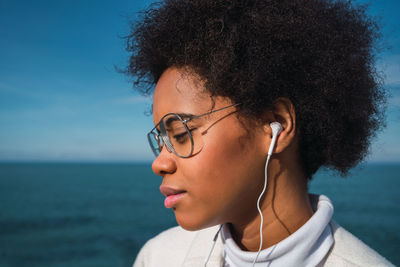 Portrait of young woman looking away against sea