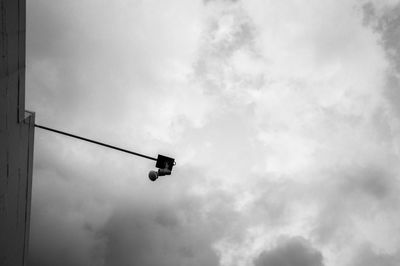 Low angle view of light fixture on building against cloudy sky