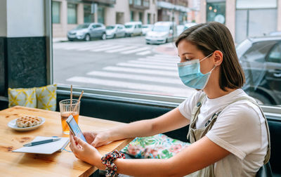 Young woman using mobile phone on table