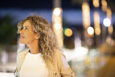 Portrait of woman looking at illuminated city