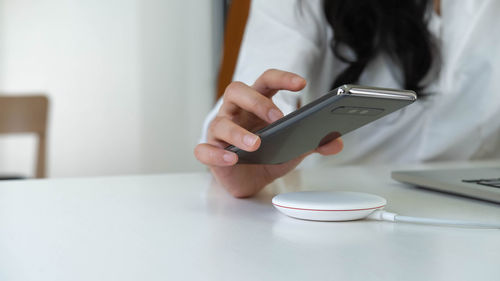 Midsection of man using mobile phone on table