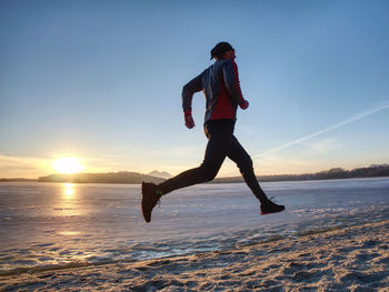 Winter training. runner in winter landscape with blue sky sunset over the frozen lake