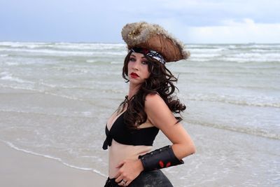 Young woman standing at beach against sky