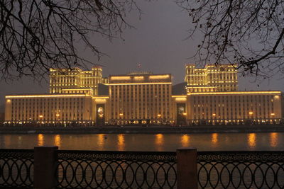 Illuminated city by river at night