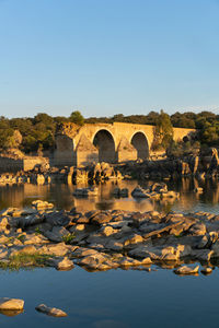 Arch bridge over river against clear sky