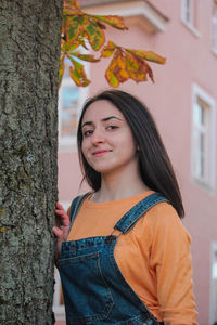 Portrait of smiling young woman standing by tree