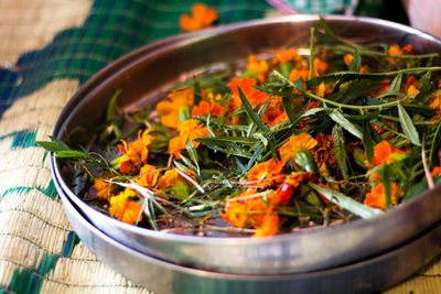 High angle view of marigolds and leaves in container