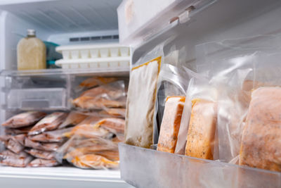 Freezer of modern refrigerator full of frozen food products, freeze cooked salmon in vacuum packs