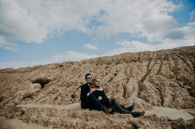 A couple in love is sitting hugging against the backdrop of mountains celebrating halloween in costu