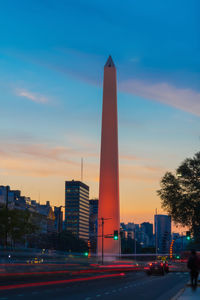 View of illuminated city street against blue sky during sunset