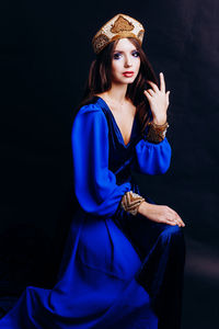 Portrait of beautiful woman in traditional clothing against black background