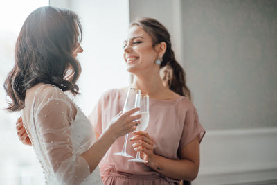 Bridesmaid and bride holding champagne flute