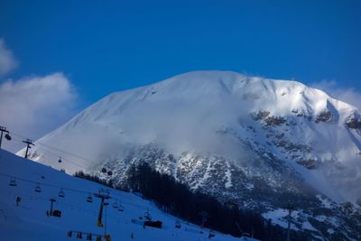 Low angle view of snowcapped mountains against blue sky