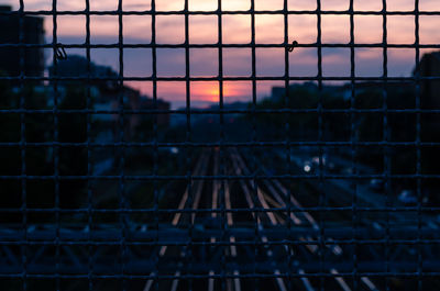 Full frame shot of chainlink fence against sky during sunset