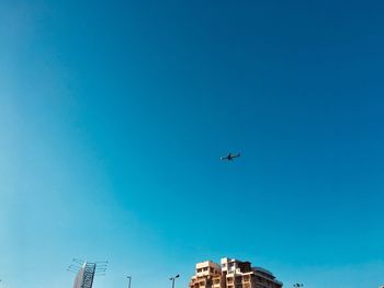 Low angle view of airplane flying against clear blue sky
