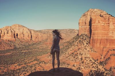 Rear view of man standing on rock against sky