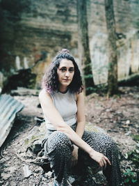 Portrait of young woman sitting on land in forest