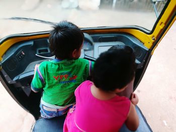 Rear view of siblings siting jinriksha