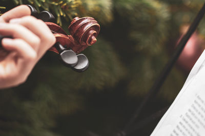 Close-up of cropped hand playing musical instrument by christmas tree