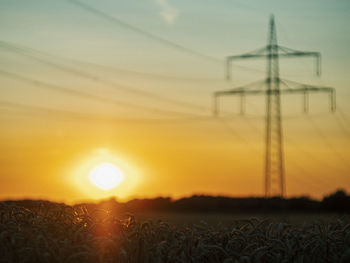 Electricity pylon on field against sky during sunset