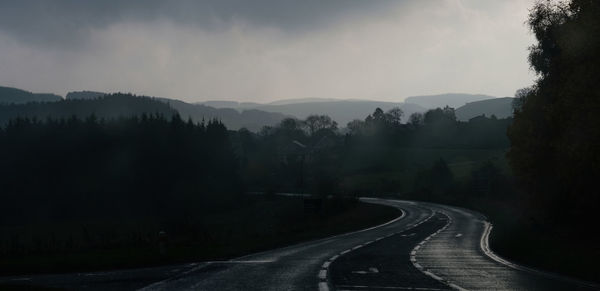 Road amidst trees against sky