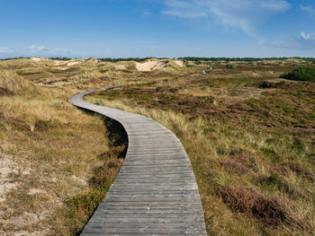 Boardwalk on field against sky