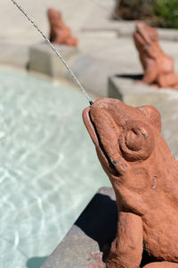 Close-up of frog shape fountain on sunny day