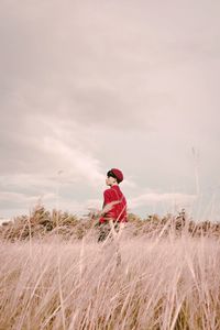 Woman standing on field against sky