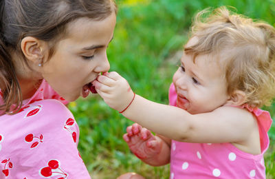 Baby girl feeding berry to sister