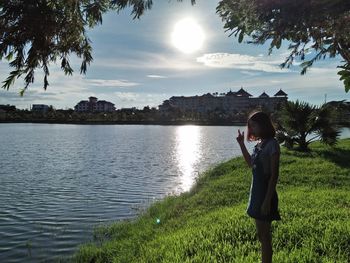 Rear view of woman photographing lake against sky