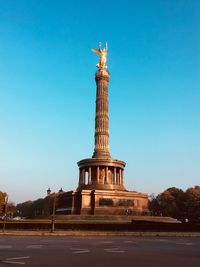 Low angle view of historic statue in city against blue sky