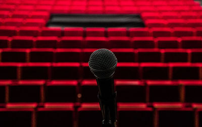 Close-up of microphone against empty red seats in auditorium