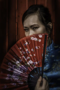 Portrait of woman holding folding fan