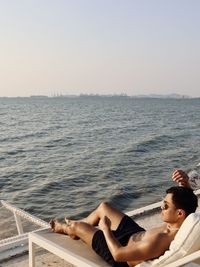 Portrait of woman sitting on sea against clear sky