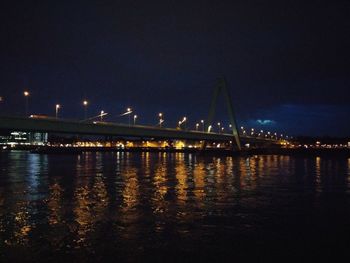 Illuminated bridge over river against sky at night