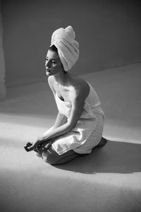 Woman wearing towels while sitting on floor at home