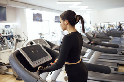 Side view of young woman using mobile phone in gym