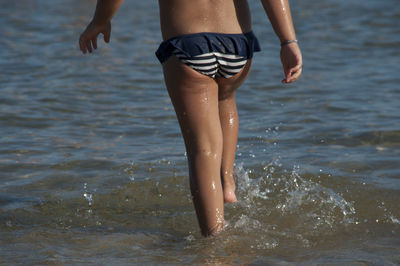 Low section of girl walking on shore at beach