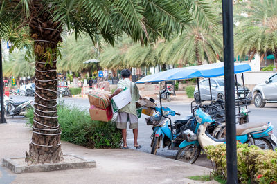 People by palm trees on street in city