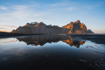 Scenic view of lake by mountains against sky during sunset