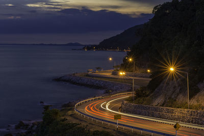 High angle view of light trails on road by sea against sky