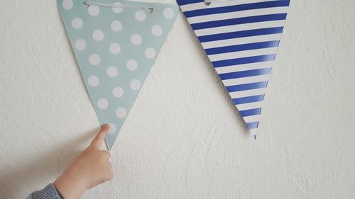 Cropped hand of baby boy playing with flags on wall at home