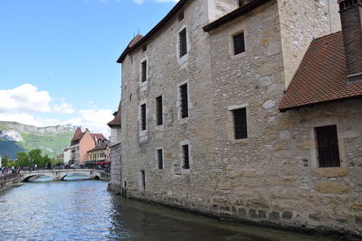 Houses by canal against sky in city