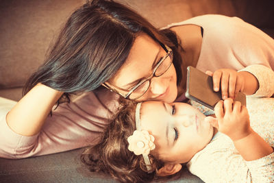 Portrait of woman lying down on smart phone at home