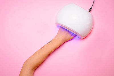 Woman's hand while taking care of her nails on pink background, flat lay