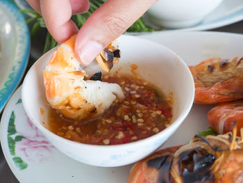 Close-up of dipping a shrimp in sauce