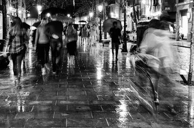 People walking on wet city street during monsoon