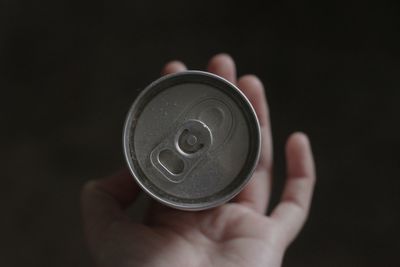 Cropped hand holding navigational compass against black background