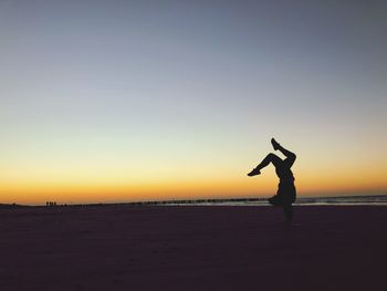 Silhouette person on beach against sky during sunset