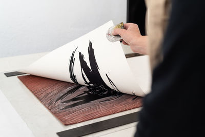 Midsection of person holding paper on table